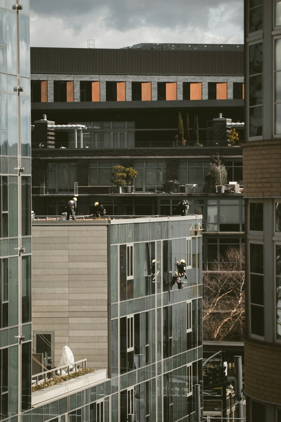 Des ouvriers nettoient les fenêtres d'un immeuble moderne de grande hauteur.